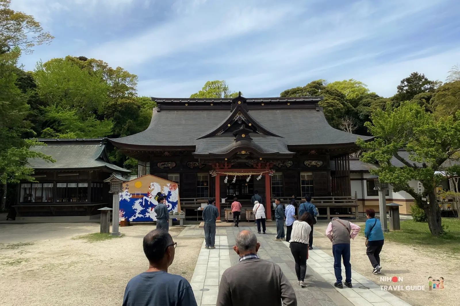Visitors standing in front of the main worship hall at Oarai Isosaki Shrine on a sunny day in Ibaraki, Japan
