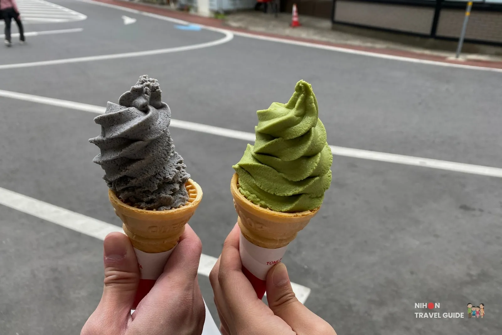 Black sesame and matcha soft serve ice cream cones held near the shops at Fukuroda Falls. 