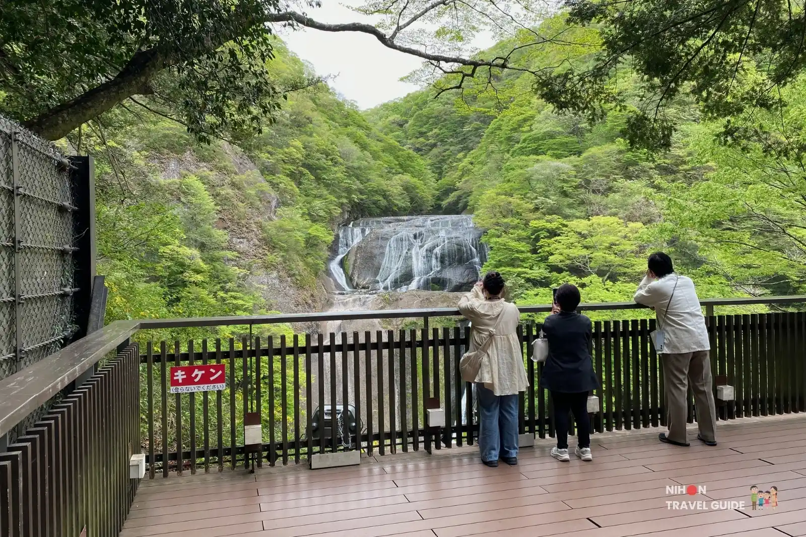 Visitors viewing Fukuroda Falls from the Level 3 observation deck, looking out over the multi-tiered waterfall and green forest