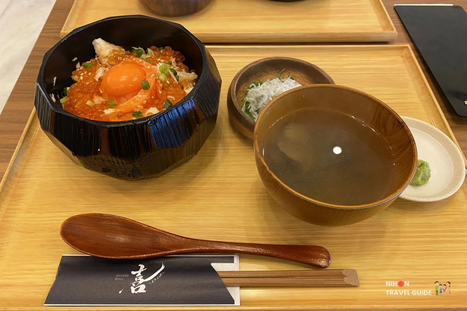 Harasu ikura salmon donburi (salmon belly and salmon roe rice bowl) with clear clam soup, shredded daikon, wasabi, and wooden utensils at a restaurant in Nakaminato Fish Market, Ibaraki