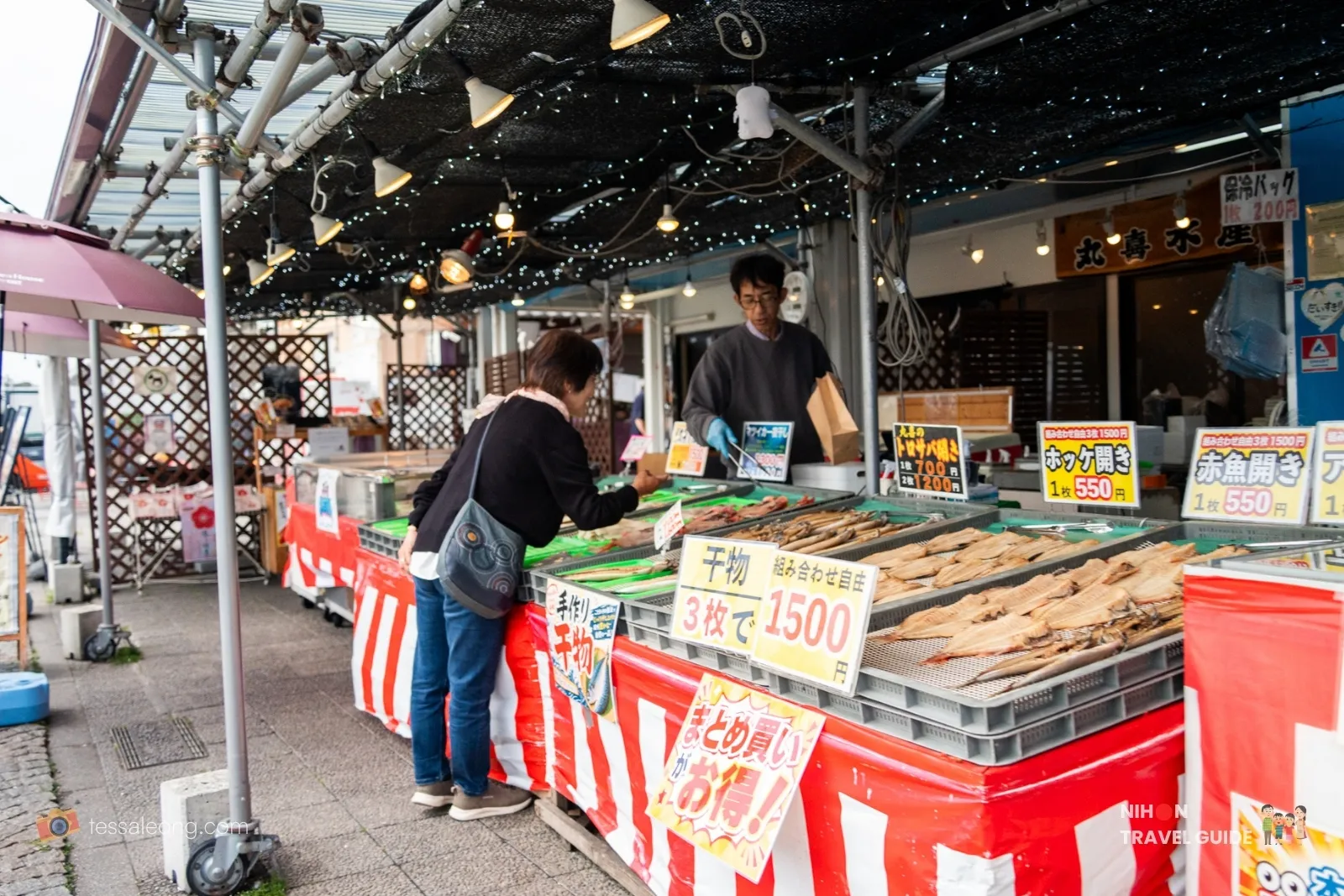 Customer selecting dried fish at a stall while the vendor assists at Nakaminato Fish Market in Hitachinaka, Ibaraki.