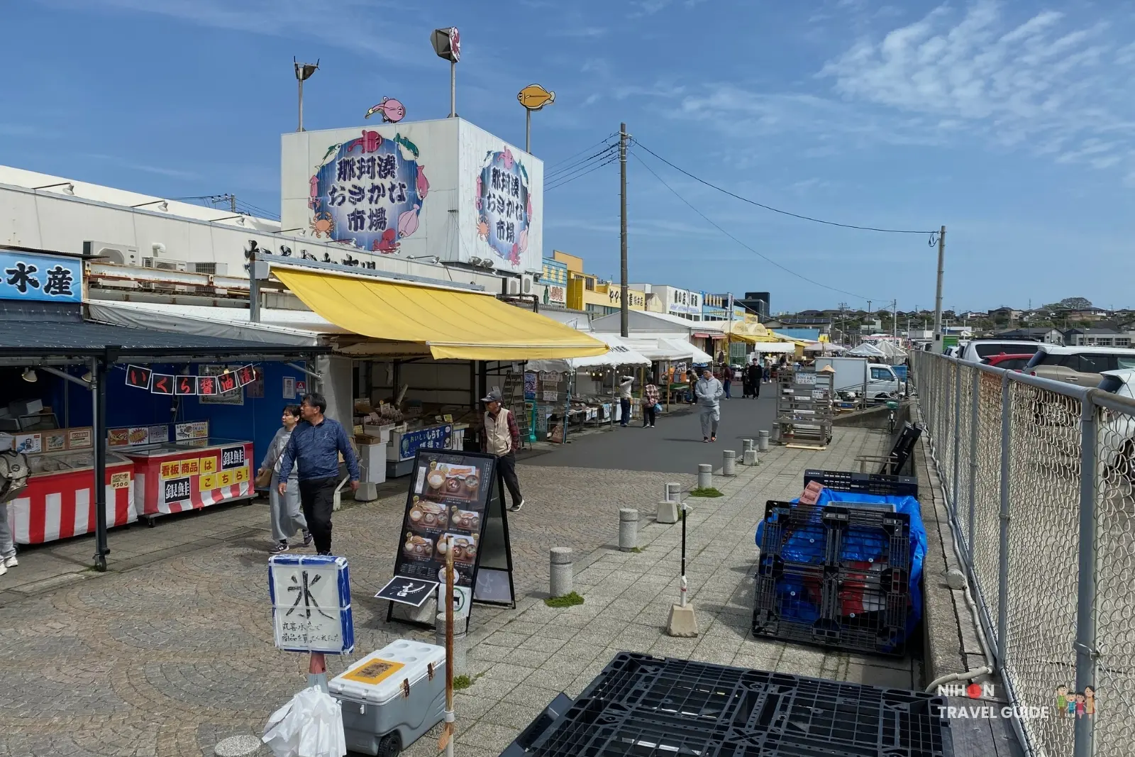 Wide view of Nakaminato Fish Market in Hitachinaka, Ibaraki, showing the main entrance area with stalls, colorful banners, and visitors on a sunny day