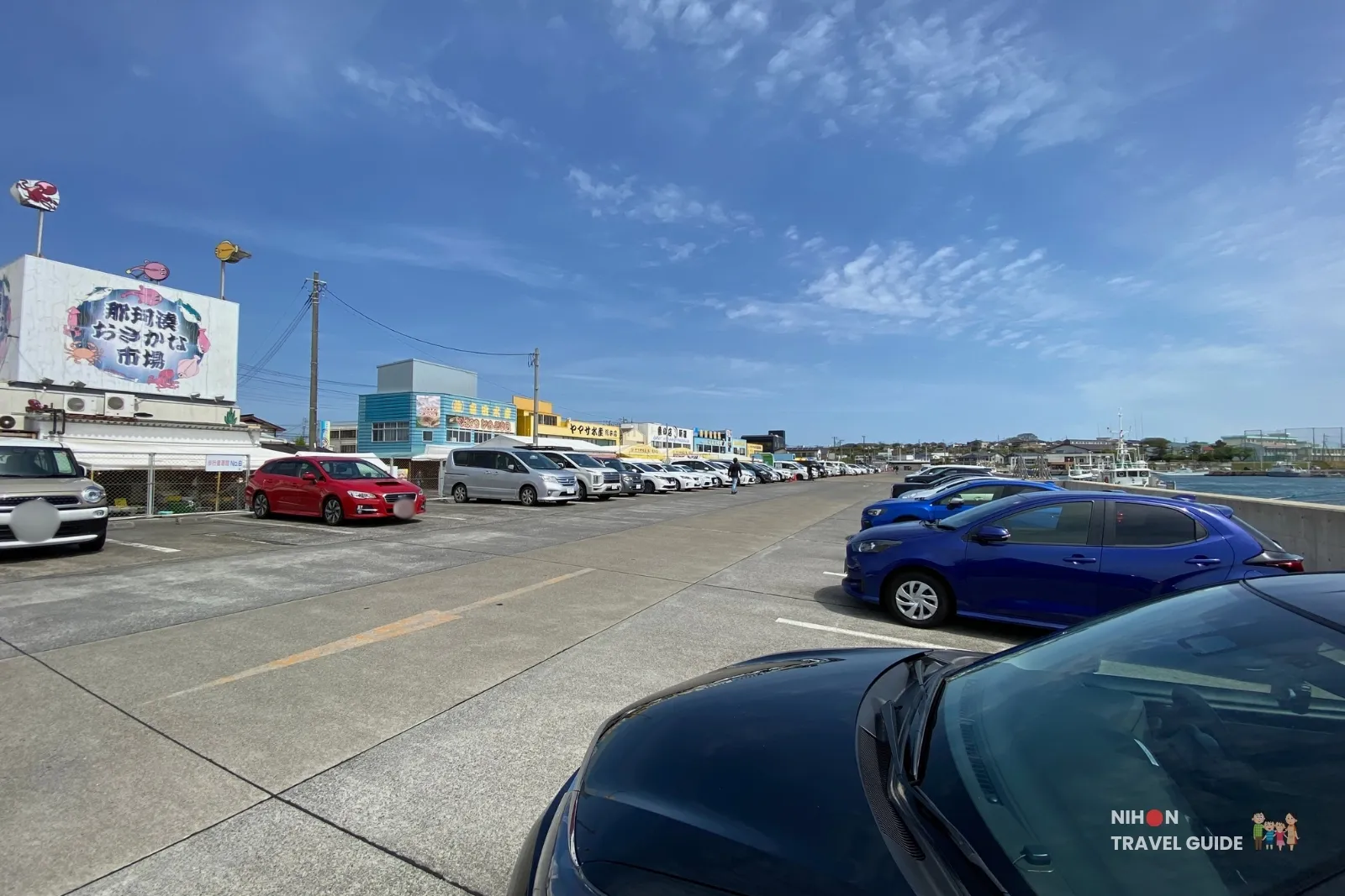 Spacious parking area at Nakaminato Fish Market with many cars parked under a clear blue sky, overlooking the market buildings and waterfront in Ibaraki.