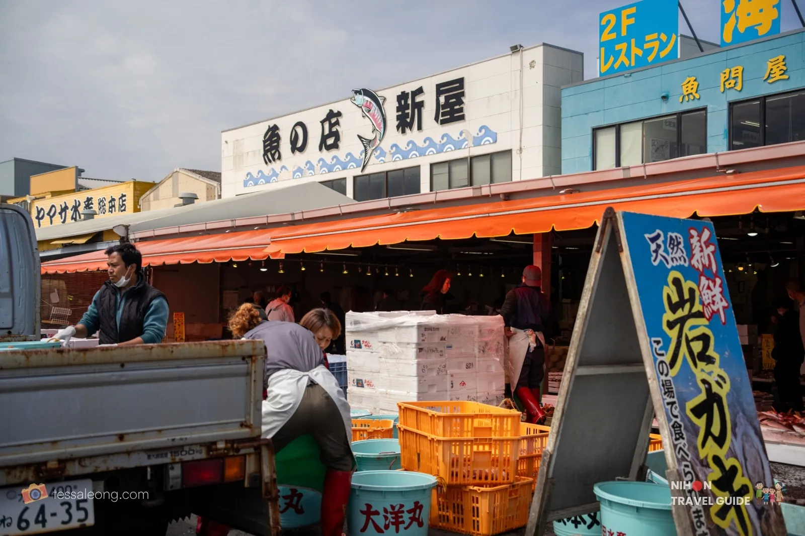 Busy scene at Nakaminato Fish Market with vendors working near a truck, orange awnings, and seafood shops in Hitachinaka, Ibaraki