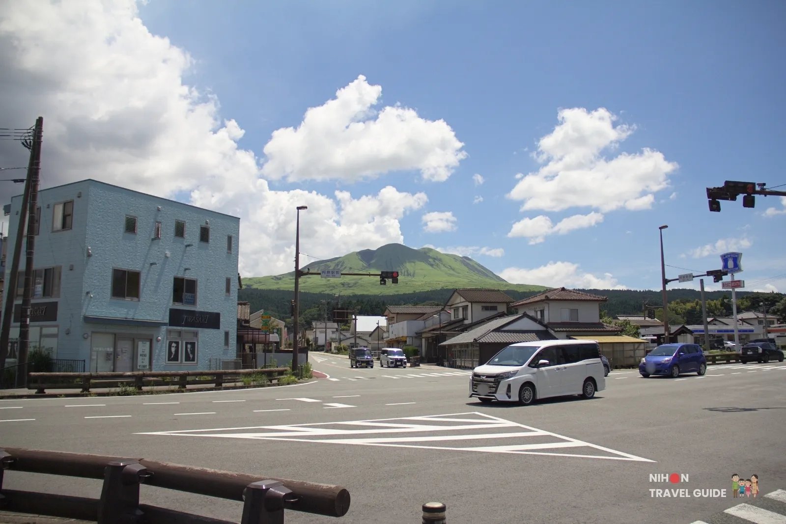 Street view near Aso Station with the green slopes of Mount Aso in the background in Kumamoto.