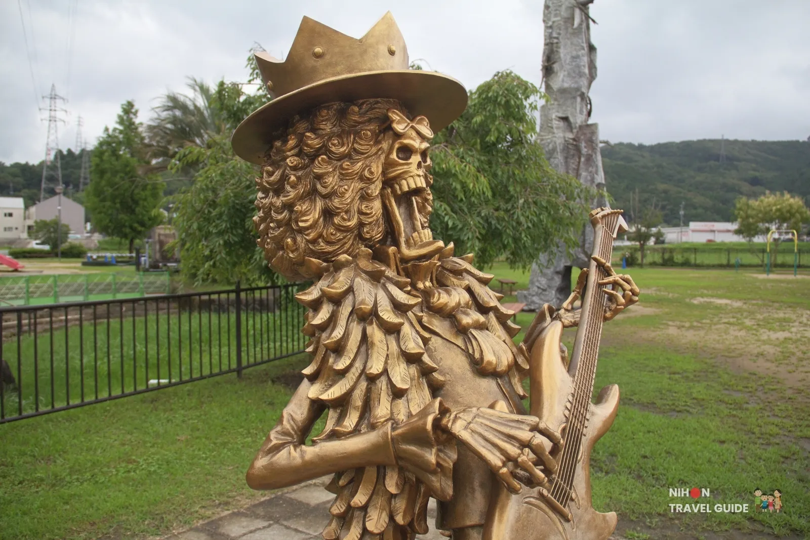 Close-up of the bronze Brook statue from One Piece playing guitar with mouth open at Mifune Fureai Park Dinosaur Park in Kumamoto.