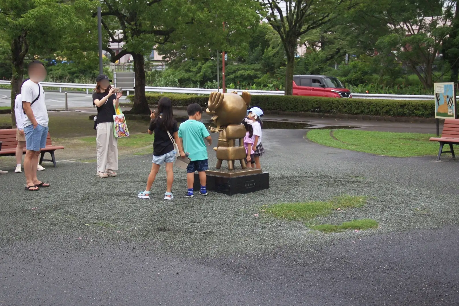 Families and children taking photos with the bronze Chopper statue from One Piece at Kumamoto City Zoo.