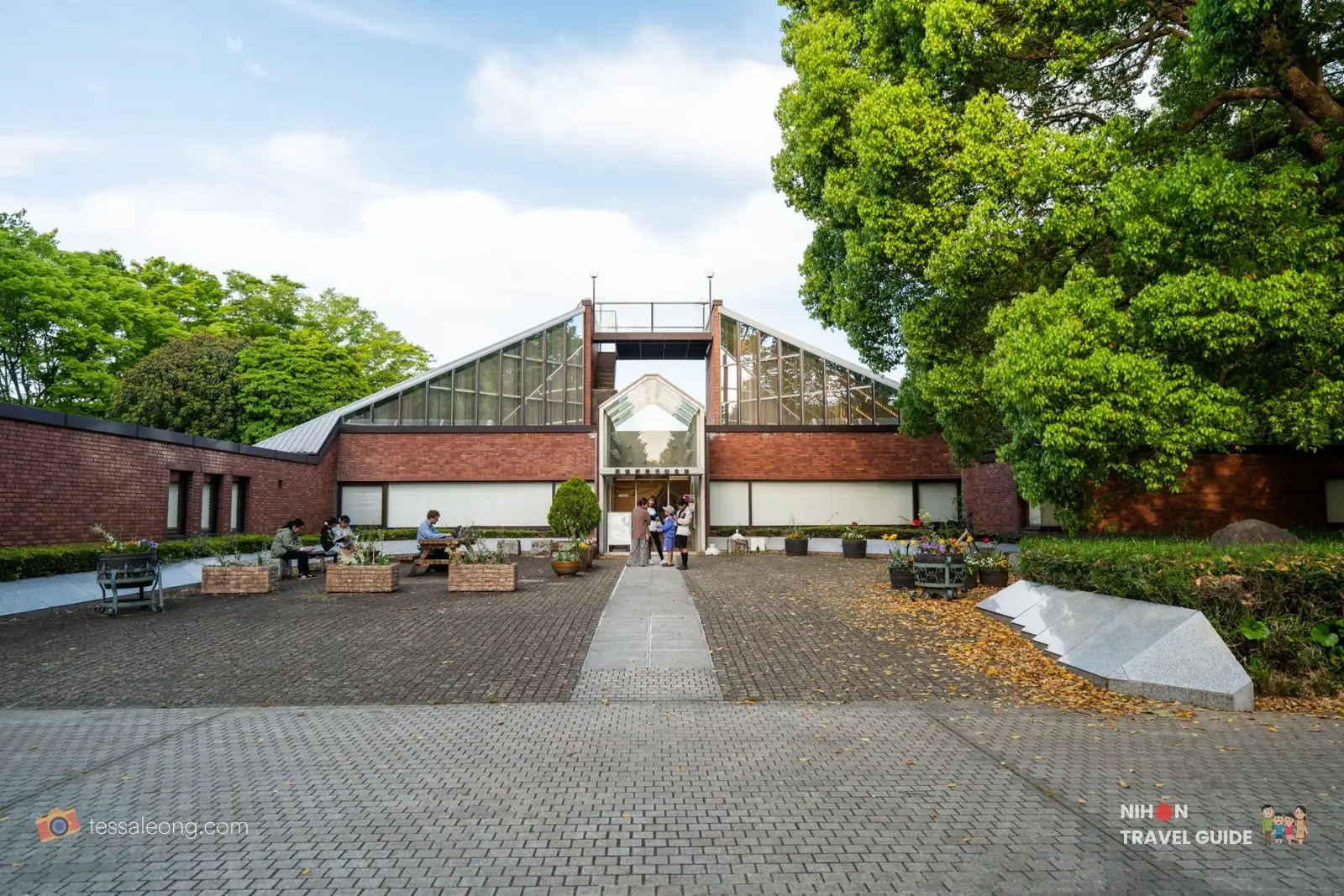 Front view of the New City Memorial Hall with visitors at Doho Park Tsukuba in spring