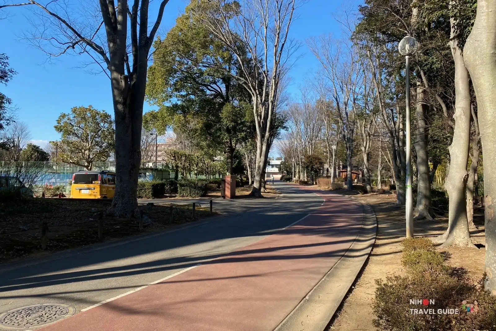 Curved walking and jogging path lined with trees at Doho Park Tsukuba during late winter
