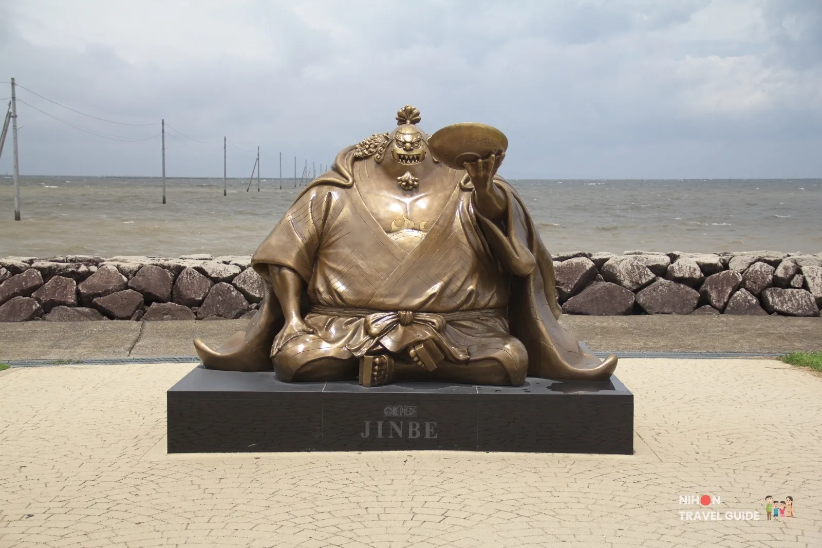 Full view of the large bronze Jinbe statue from One Piece sitting by the sea at Sumiyoshi Seaside Park in Kumamoto, Japan