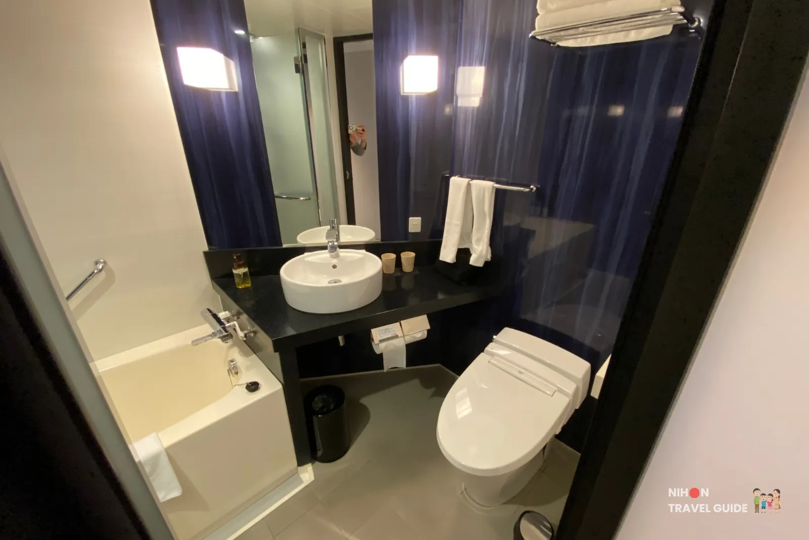 Modern bathroom at KOKO HOTEL Premier Kumamoto with toilet (washlet), vessel sink, bathtub, and dark blue accent walls.