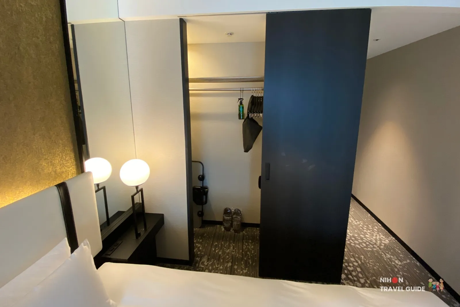 koko-hotel-premier-kumamoto-room-closet In-room closet and wardrobe space at KOKO HOTEL Premier Kumamoto, featuring hanging rail, hangers, slippers, and bedside lamps.