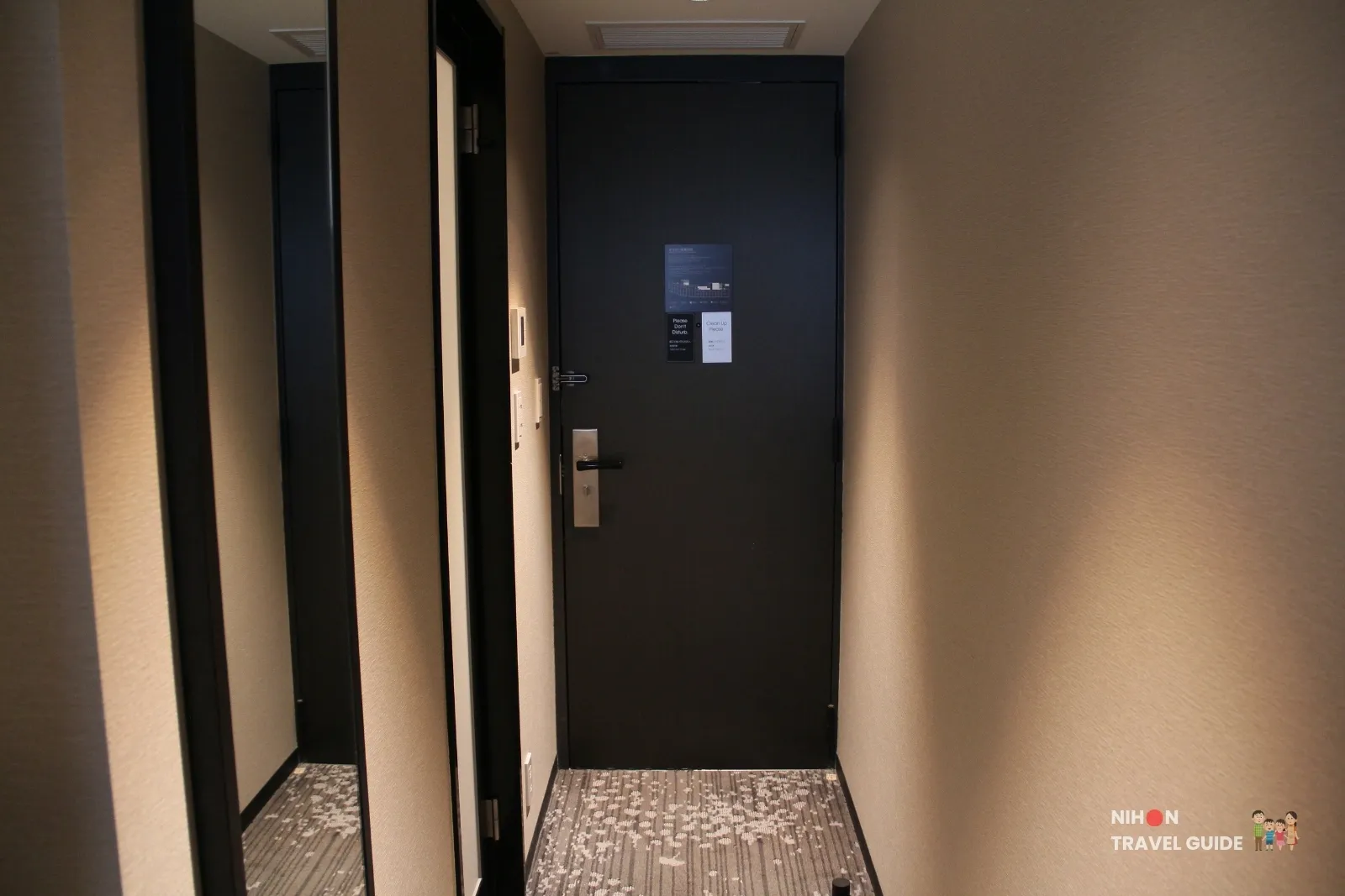 Entrance door of a guest room at KOKO HOTEL Premier Kumamoto, with privacy signs and full-length mirror in the entryway.