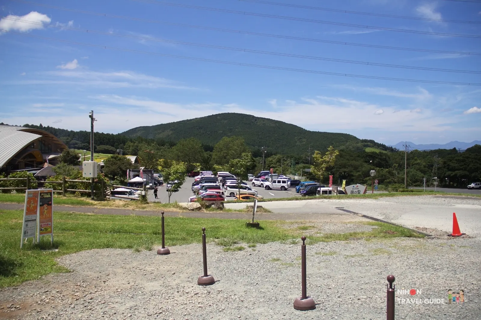 Parking lot and visitor facilities at Moe no Sato with green hills in the background in Kumamoto.