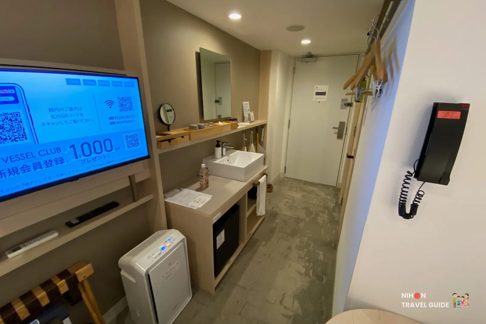 Entrance corridor of the Single Room with Shower Booth at REF Kumamoto by Vessel Hotels, showing the wall-mounted TV, open sink vanity, air purifier, mini-fridge and door