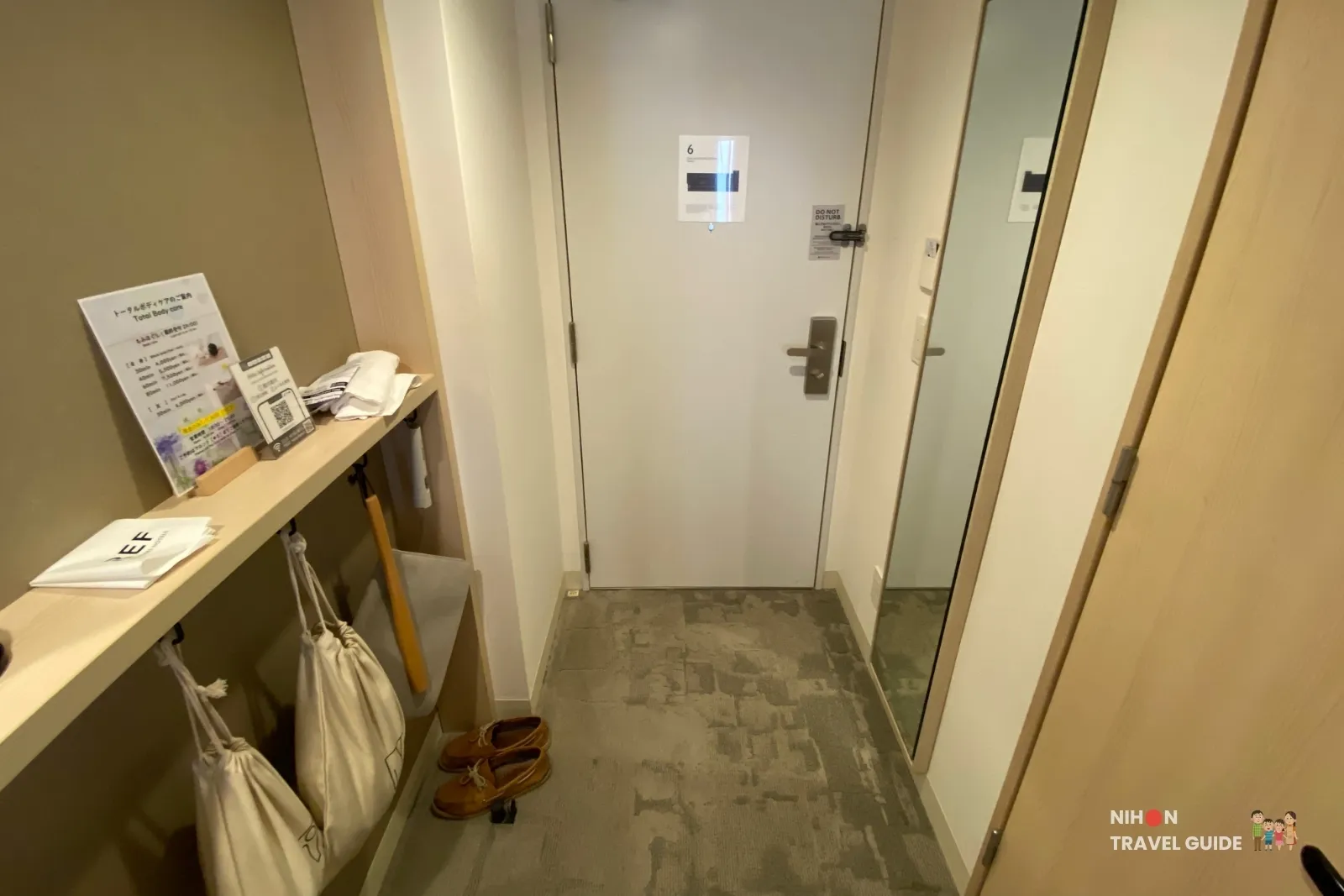 Entrance area of the Single Room with Shower Booth at REF Kumamoto by Vessel Hotels, featuring the room door, full-length mirror, wall shelf with bags, shoes and total body care information.