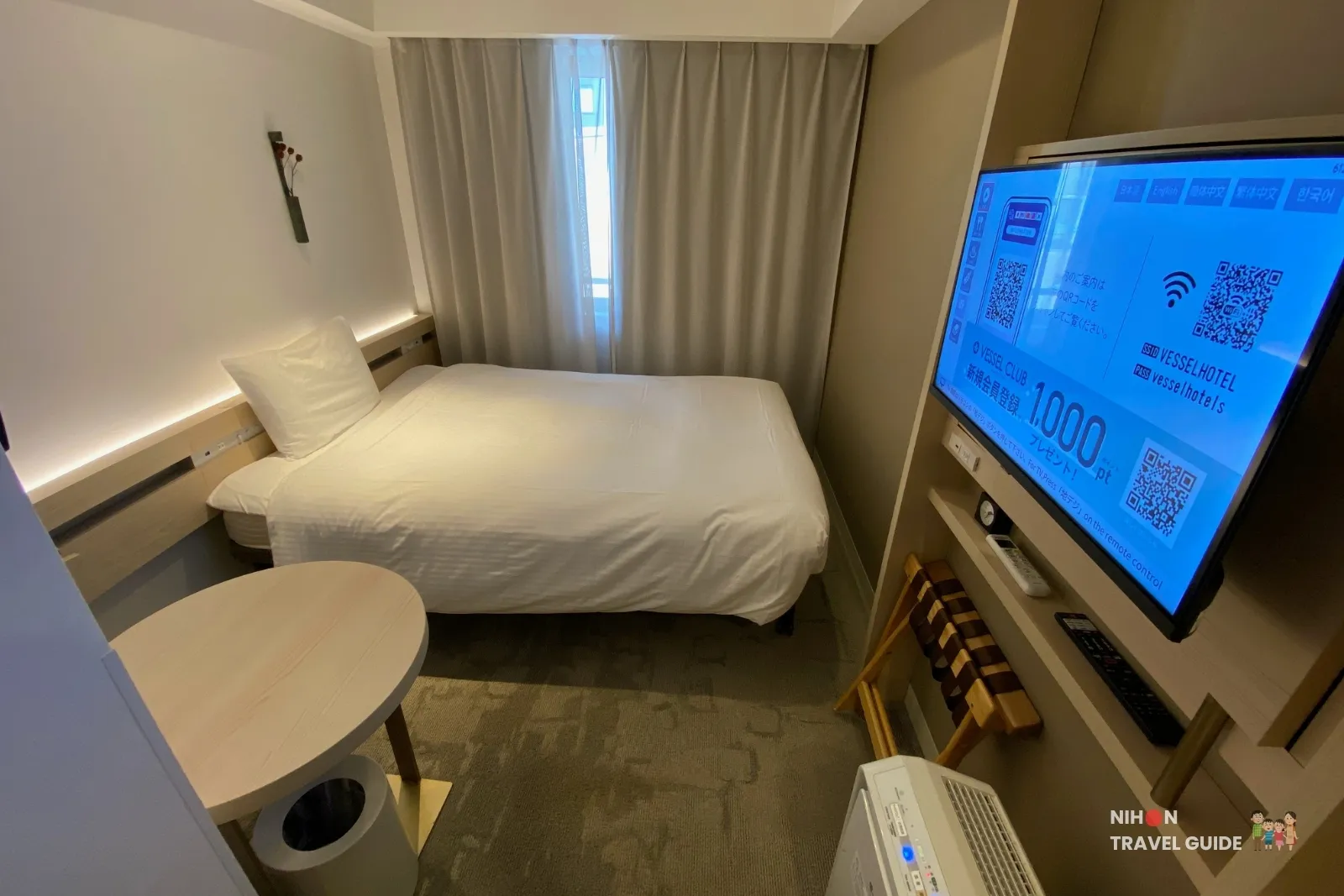 Overview of the Single Room with Shower Booth at REF Kumamoto by Vessel Hotels, showing the 140 cm bed, round side table, wall-mounted TV, luggage rack and air purifier