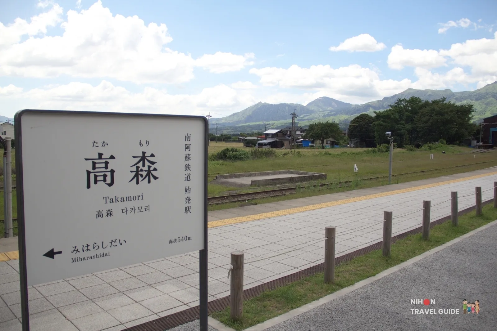 Station name sign at Takamori Station on the Minamiaso Railway with Aso mountains in the background in Kumamoto.