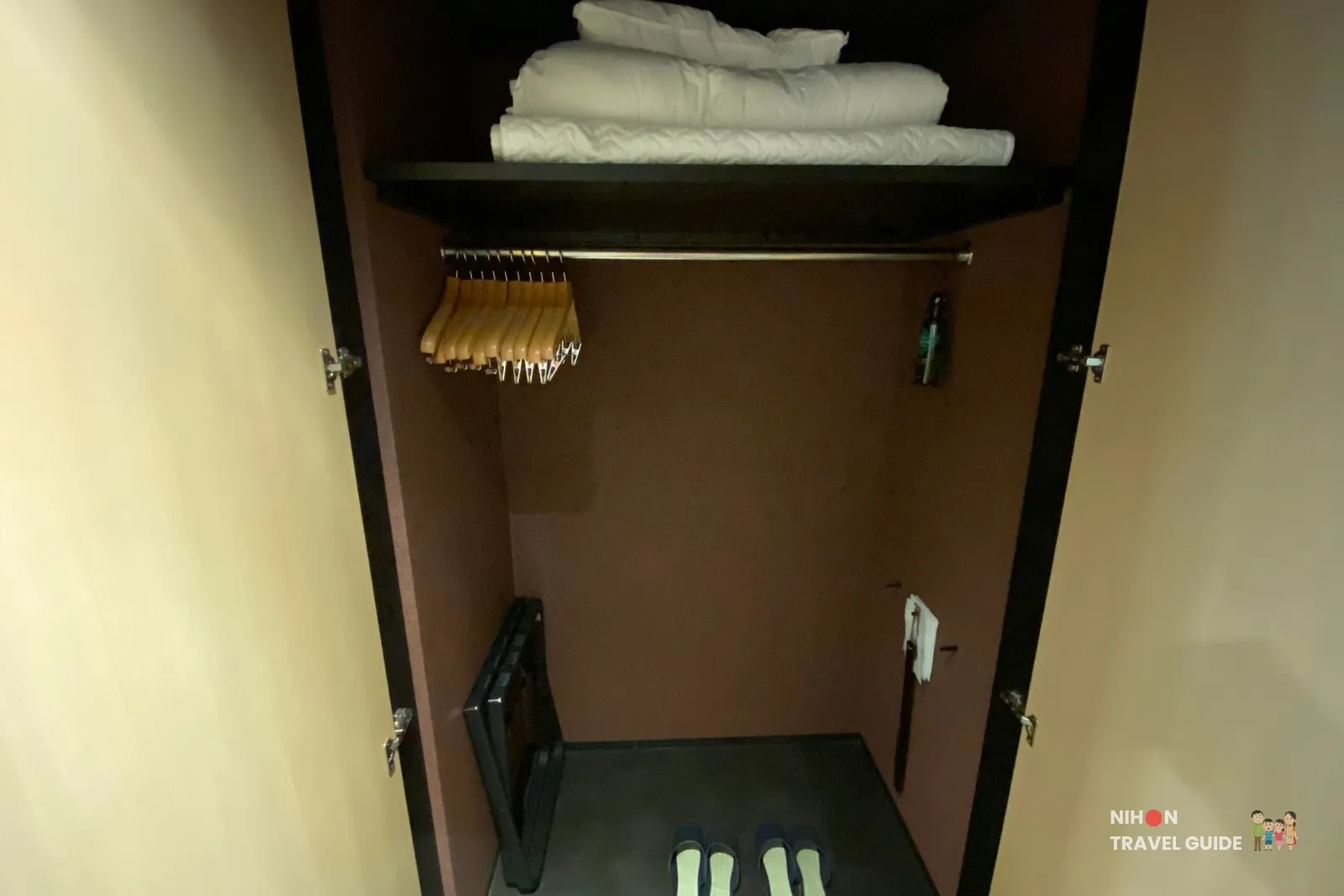 Closet in The358 SORA room with extra duvet, hangers, slippers and a folding luggage rack