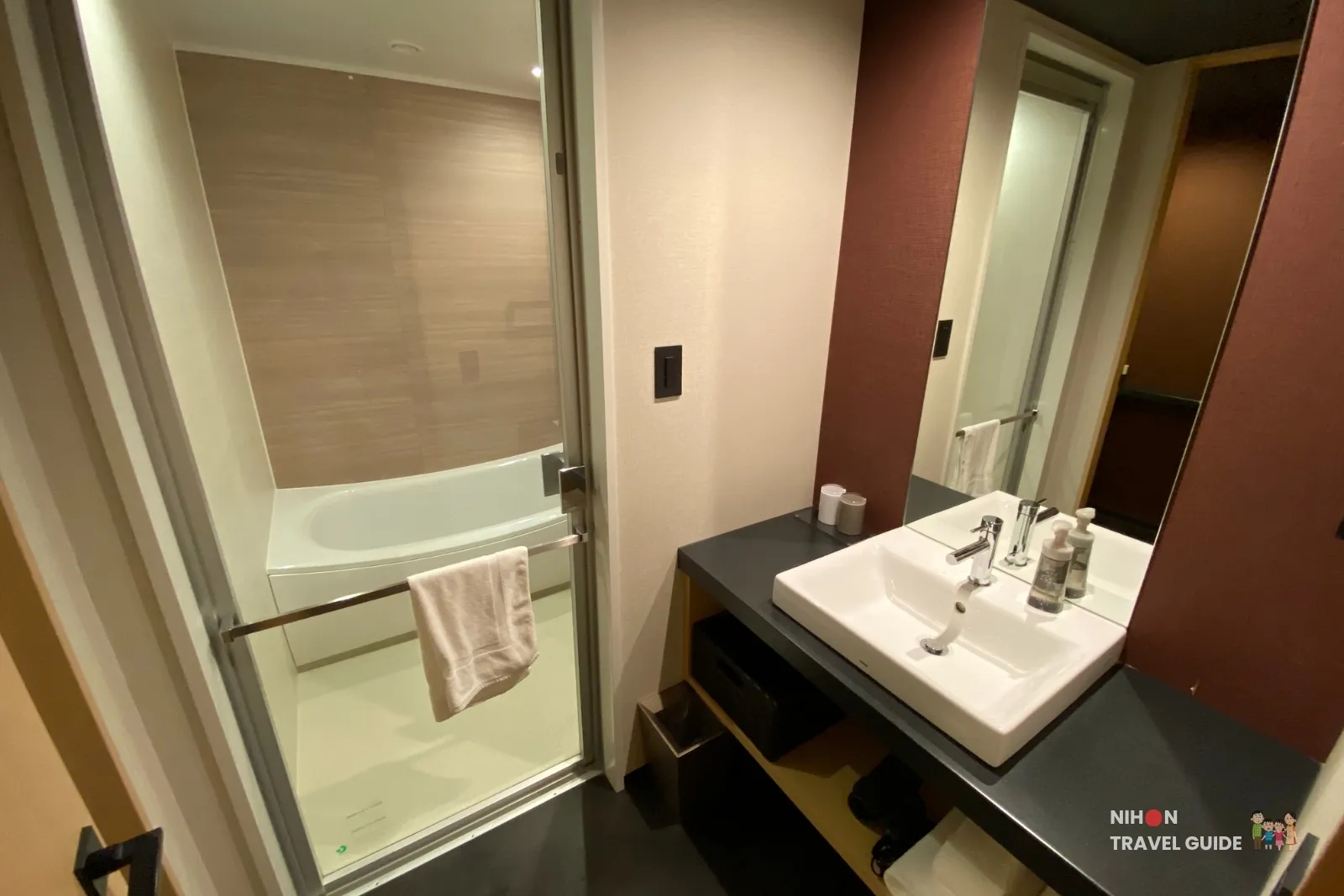 Split bathroom in The358 SORA Modern Japanese Premium Room, with vanity on the right and the tub behind a glass door