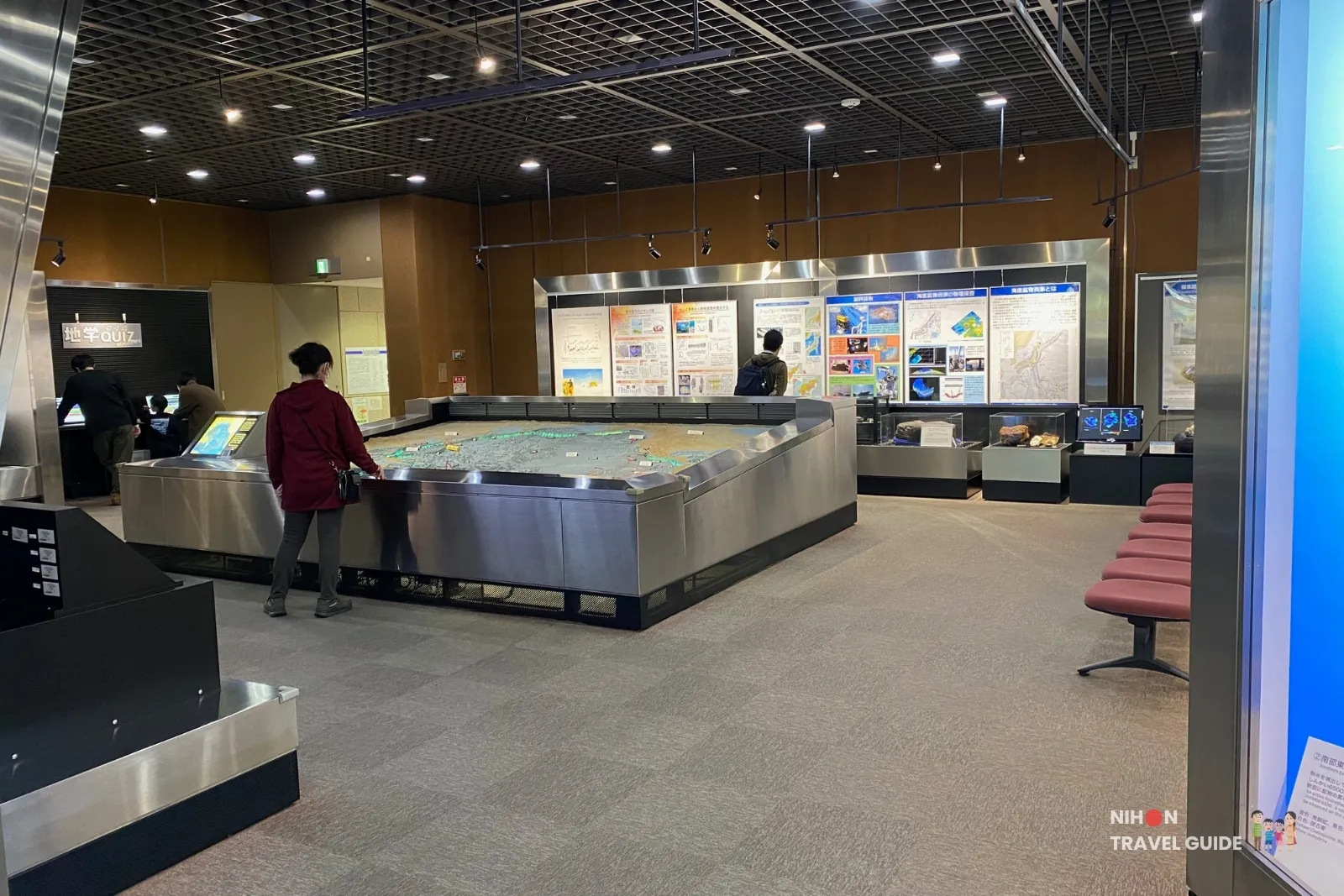 tsukuba-geological-museum-exhibition-room-2-pacific-ocean-floor-model Visitors examining the large illuminated model of the Pacific Ocean floor in Exhibition Room 2 (Natural Resources & Marine Geology) at the Tsukuba Geological Museum, surrounded by informational panels on marine geology and resources.