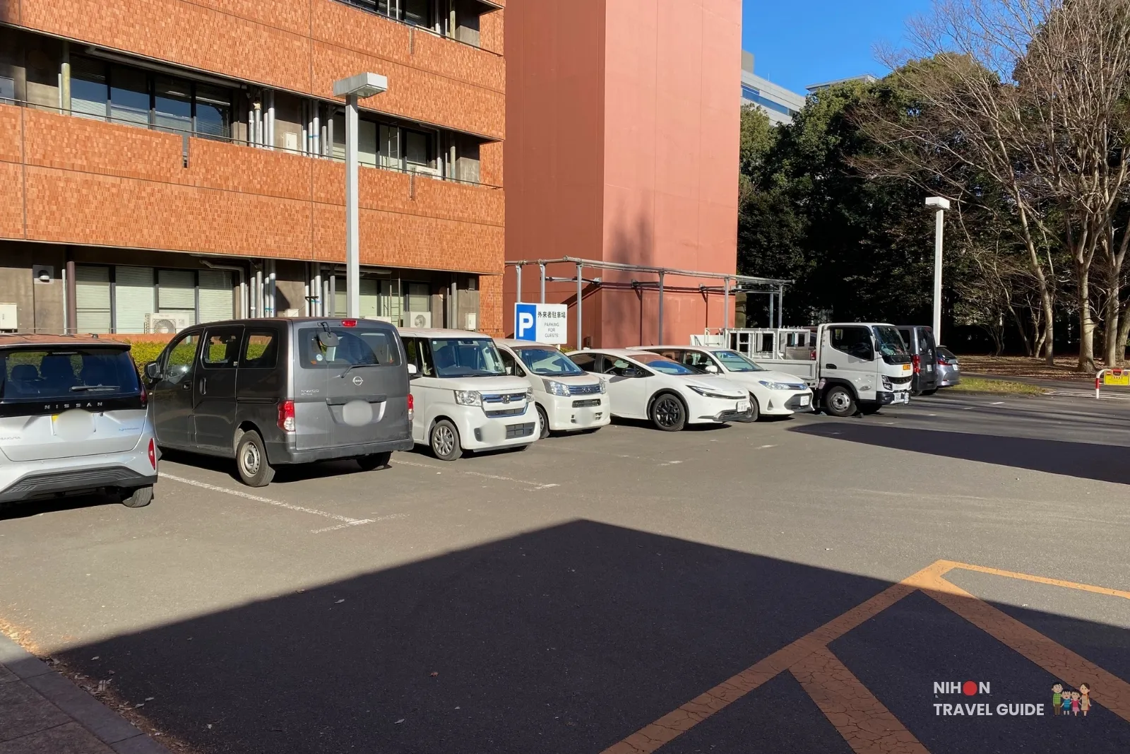 tsukuba-geological-museum-guest-parking-lot Guest parking lot outside the Geological Museum at AIST Tsukuba, with a clear “Parking for Guests” sign and cars parked next to the brick research building on a sunny day.