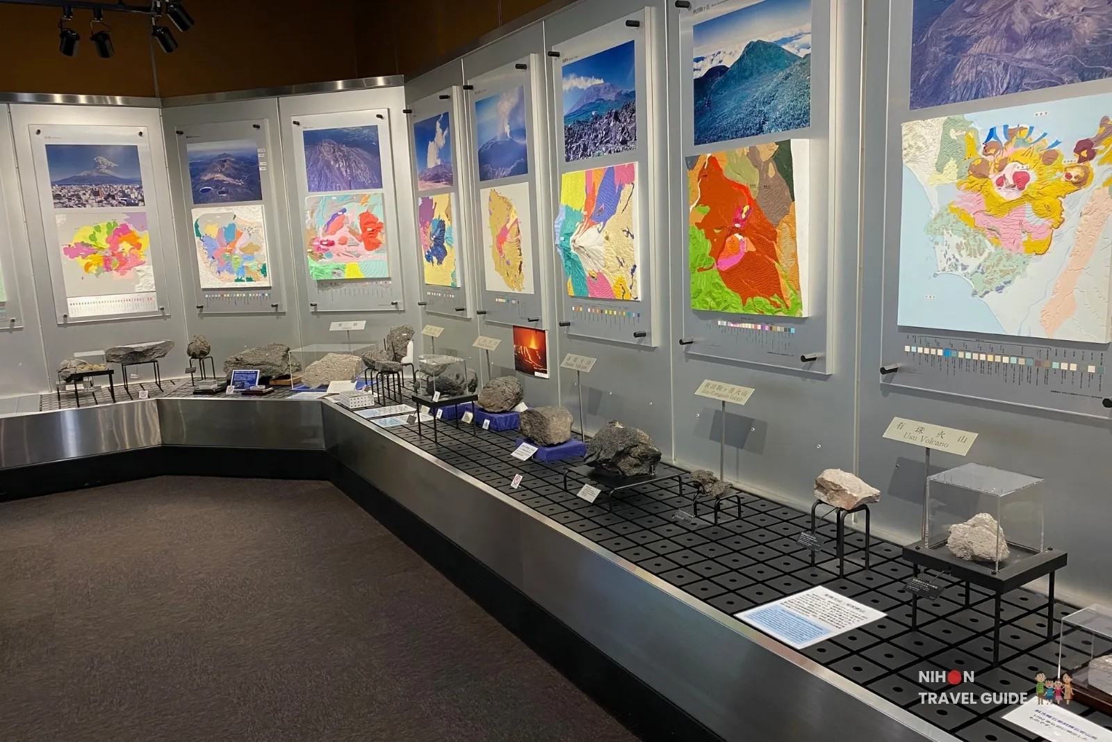 Long display wall in Exhibition Room 3 featuring geological maps and rock samples from major Japanese volcanoes, including Usu Volcano, at the Tsukuba Geological Museum.