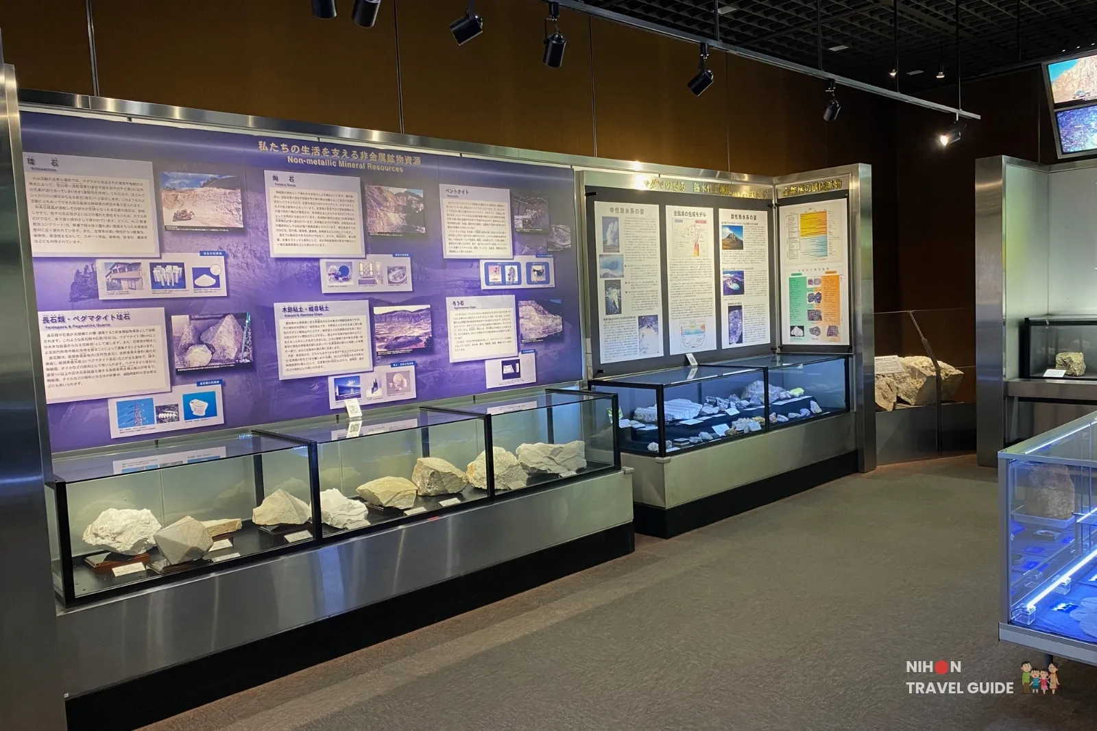Wall display of non-metallic mineral resources in Exhibition Room 2 of the Tsukuba Geological Museum, featuring explanatory panels and glass cases with white mineral specimens such as quartz and clay.