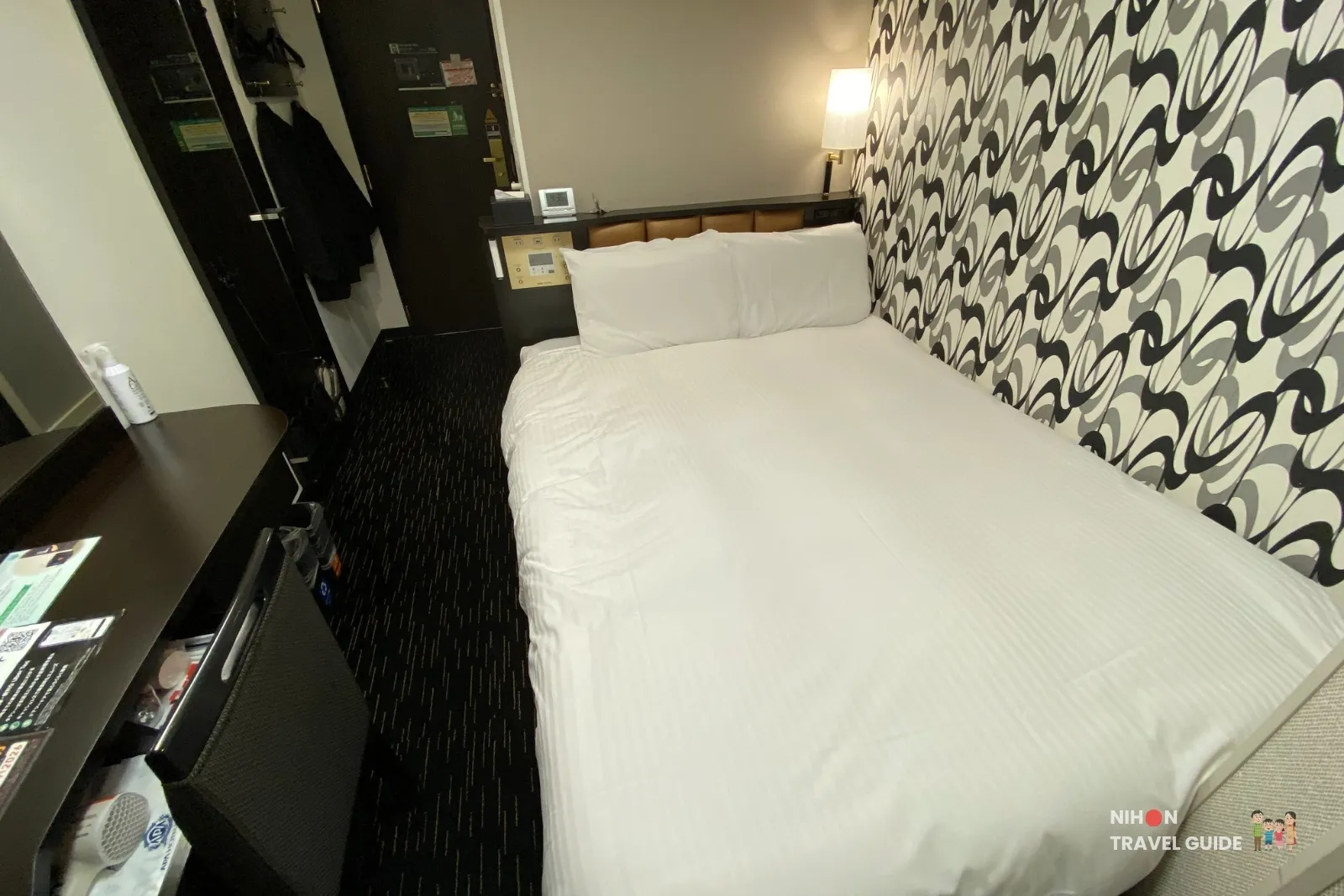 Overview of a Central standard room at APA Hotel Hakata Eki Chikushiguchi, with the double bed, bedside controls, desk, and entrance.