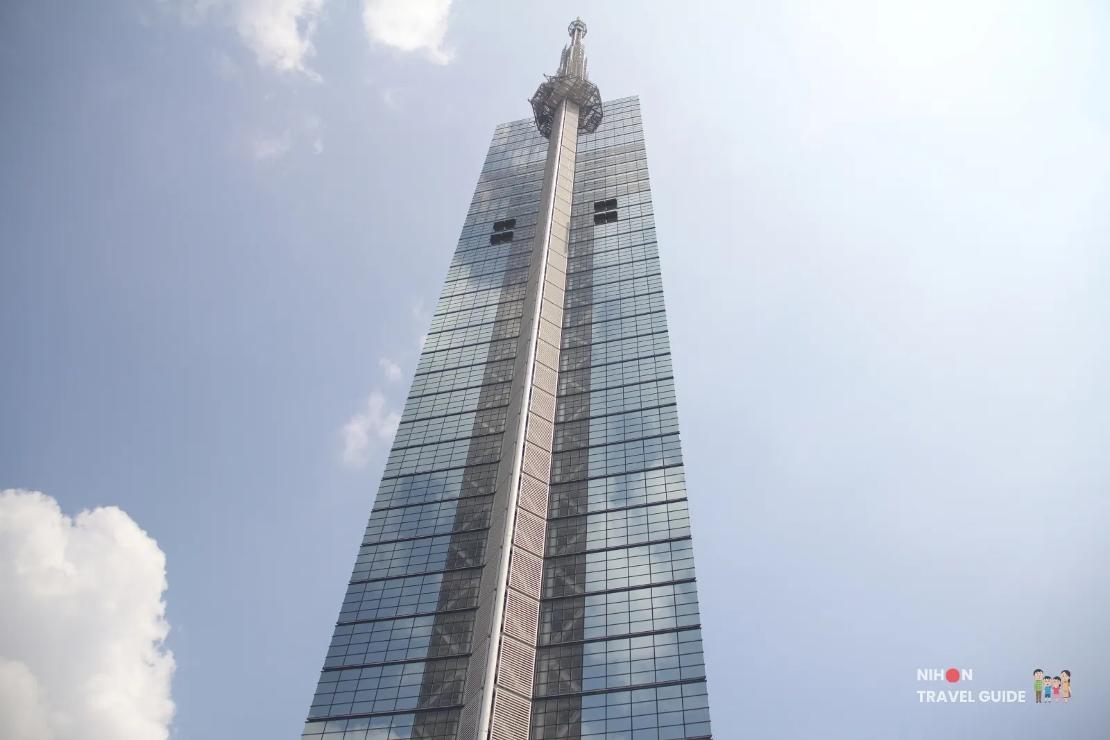 Looking up the 234-metre Fukuoka Tower glass shaft and observation windows toward the antenna mast on a bright day in Fukuoka.