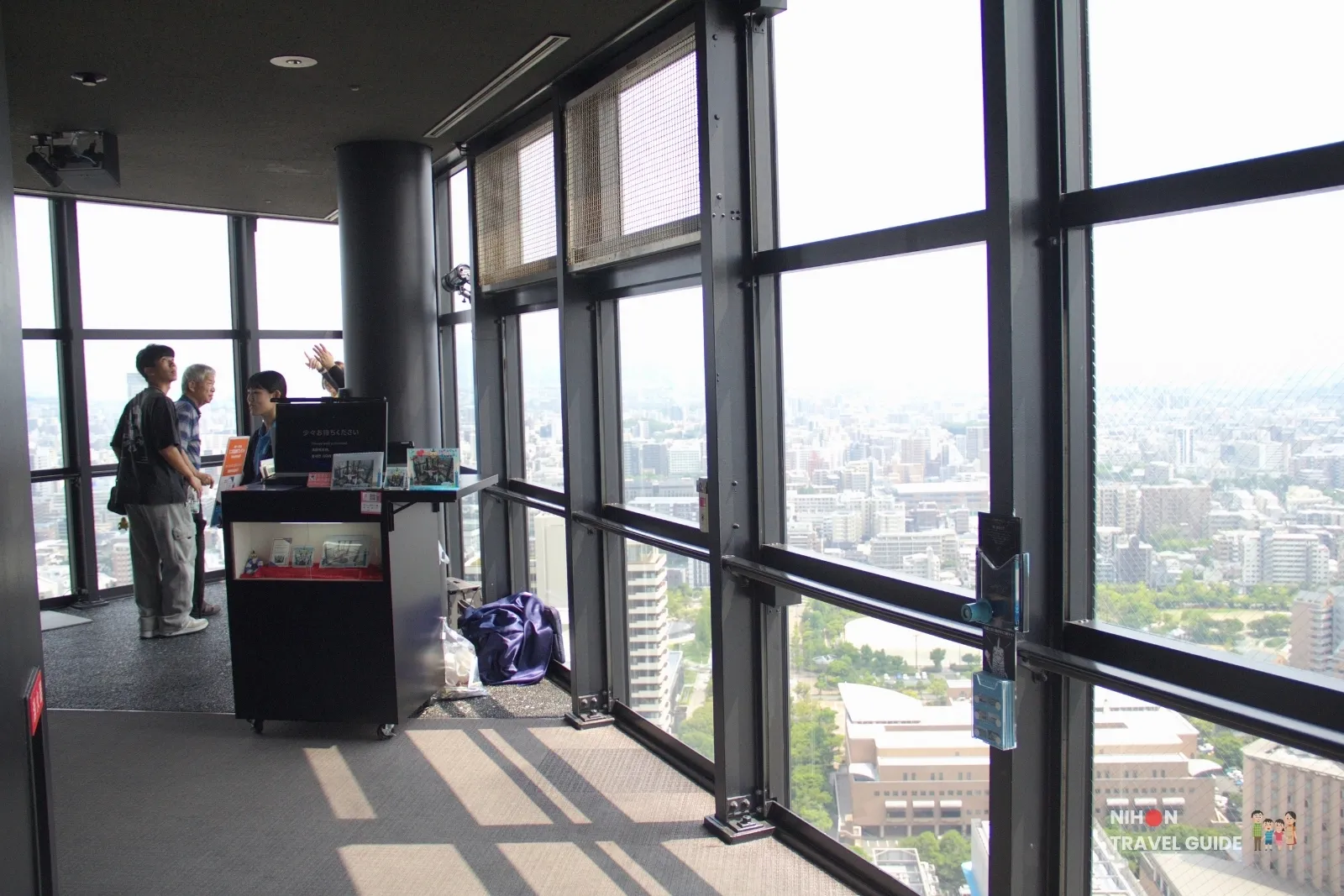 Bunkyo Studio photo corner on the Fukuoka Tower observation deck, with a staff cart by the windows overlooking the city.