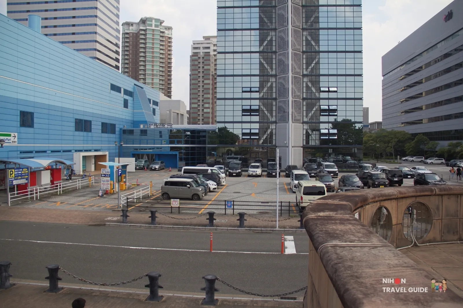 Fukuoka Tower Dai 2 Parking Lot at the rear of the tower, with cars parked beside the glass shaft and blue annex.