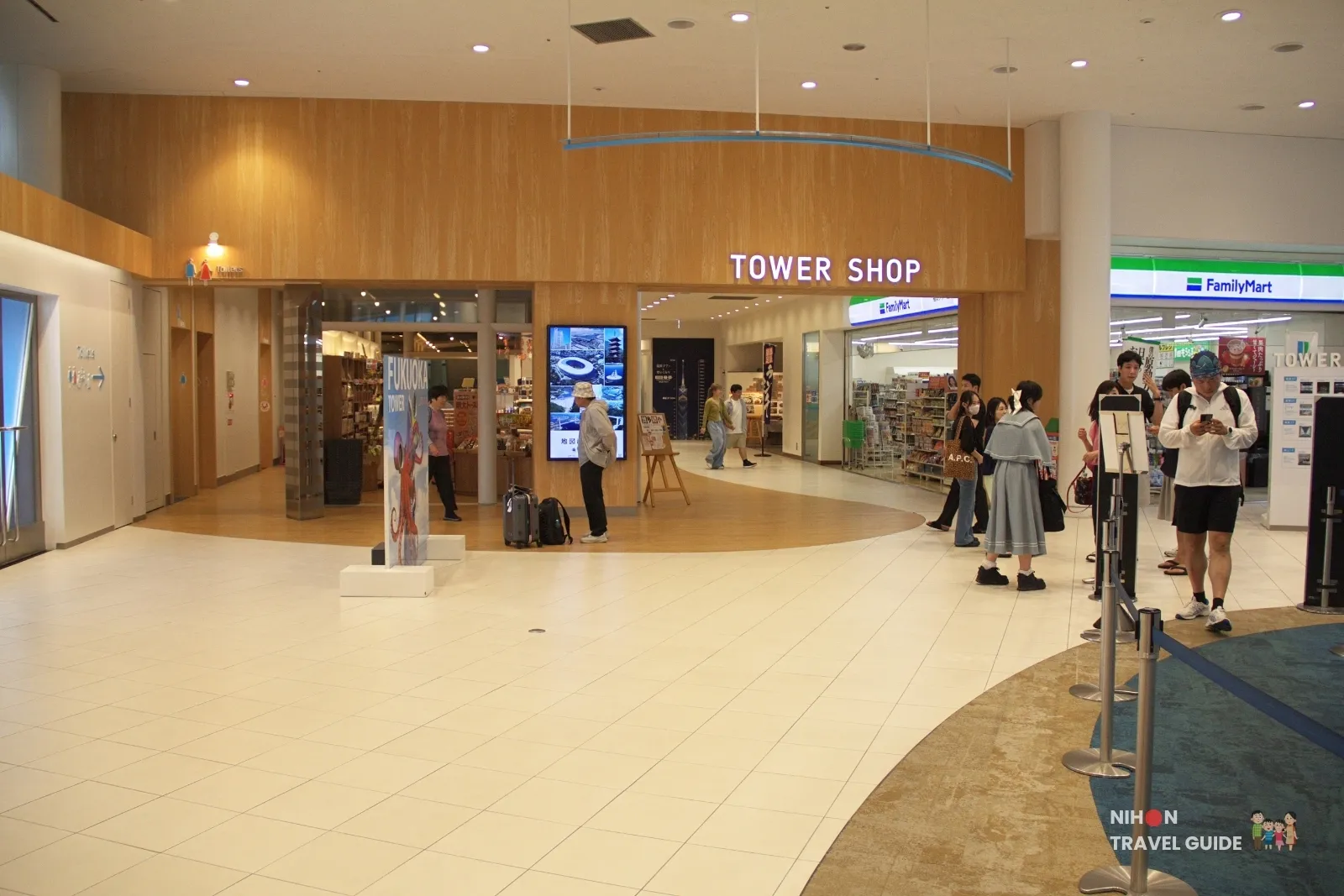 Ground-floor Tower Shop entrance at Fukuoka Tower next to FamilyMart, with visitors in the SKY Port lobby.