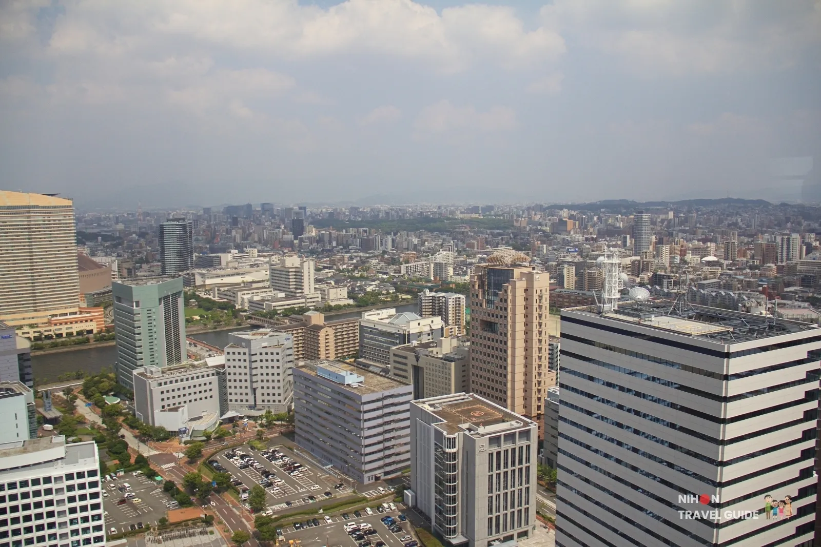 View from Fukuoka Tower past Hilton Fukuoka Sea Hawk and Momochi offices along the river toward central Fukuoka and a belt of park greenery.