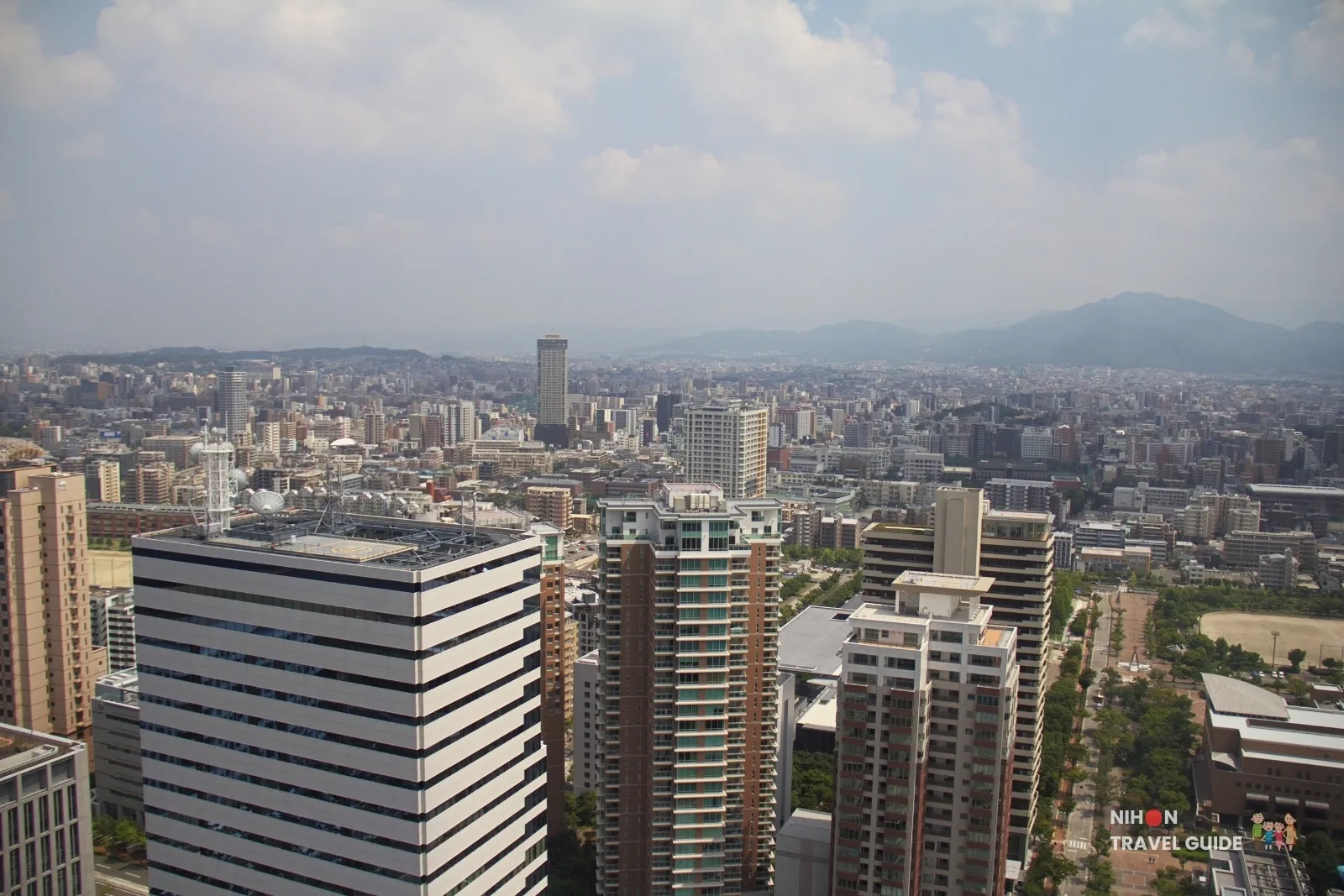 View from Fukuoka Tower over Momochi high-rises toward inland Fukuoka, with Mount Aburayama on the right horizon.
