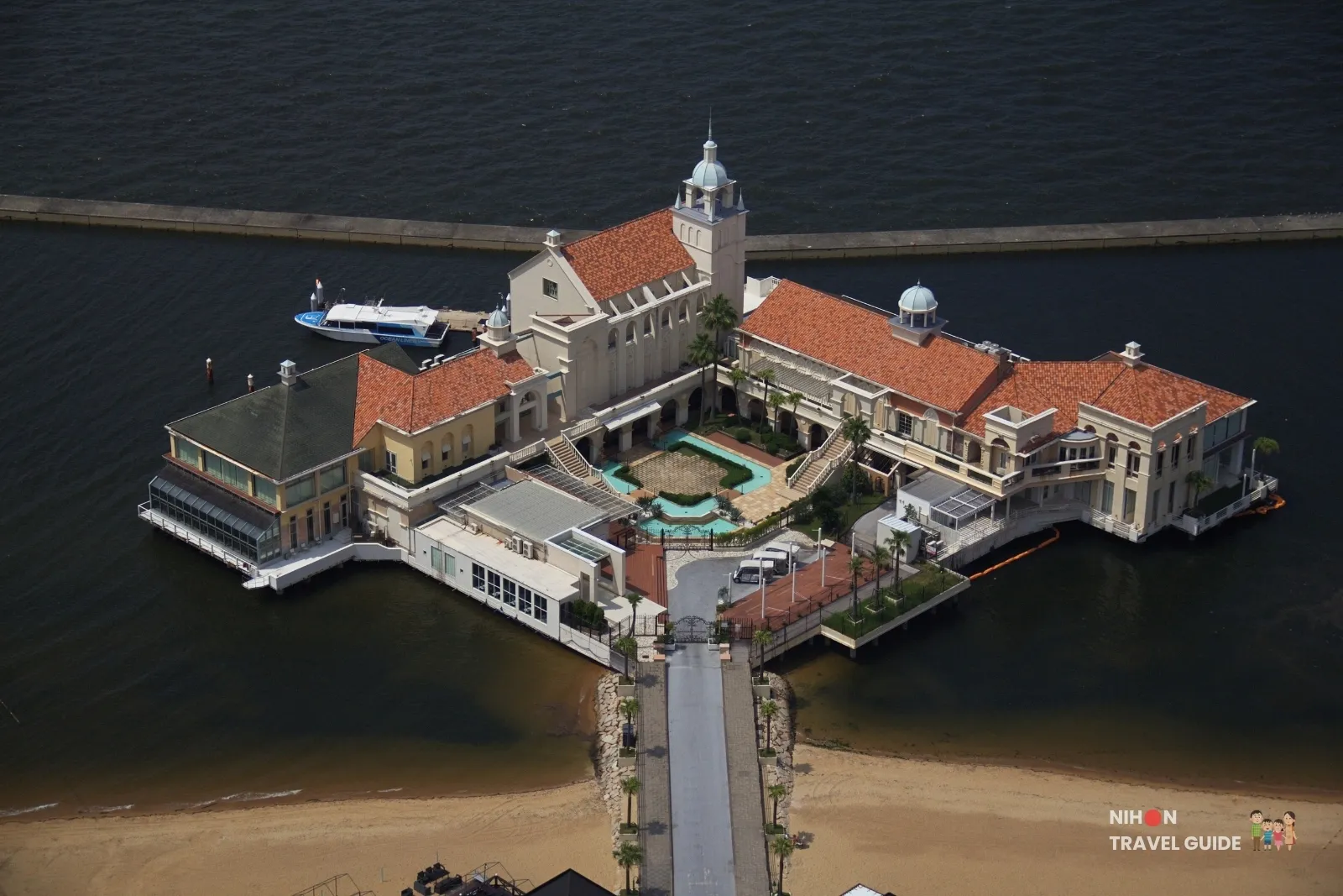 Aerial view from Fukuoka Tower of Marizon’s red-roofed pier complex and chapel on Hakata Bay, with a sightseeing boat at the dock.