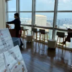 Window counter seats at Sky Cafe & Dining Refuge on Fukuoka Tower observation 2F, looking over Hakata Bay and the city.