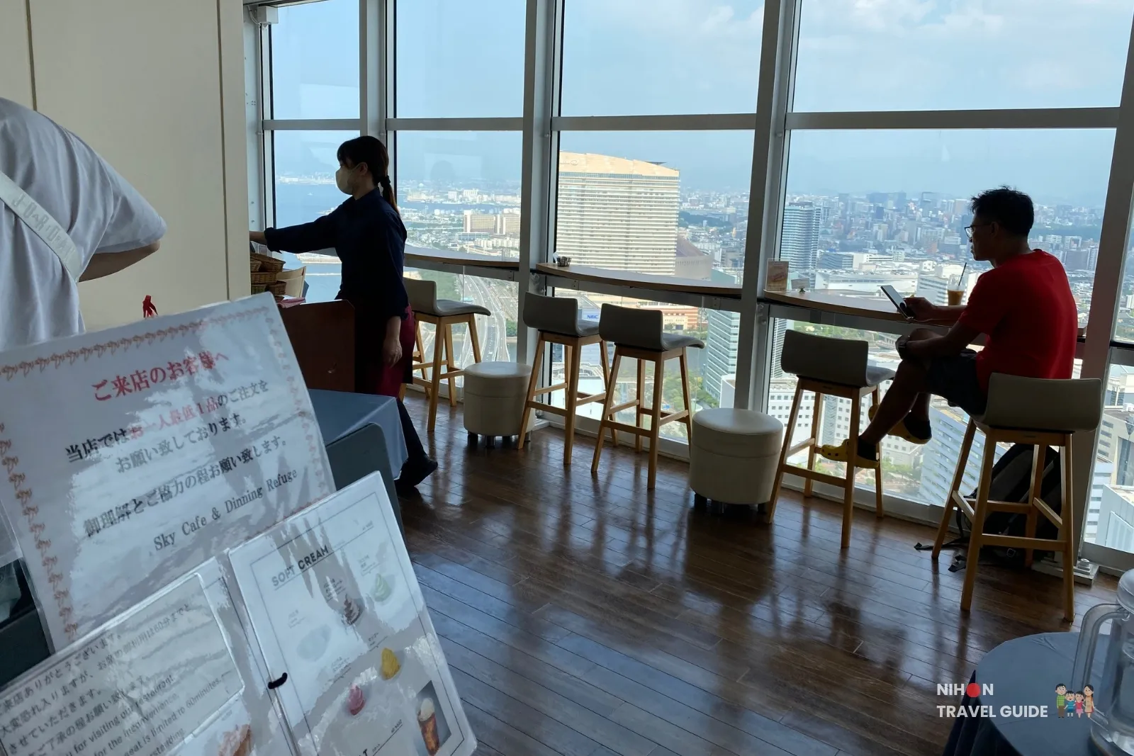 Window counter seats at Sky Cafe & Dining Refuge on Fukuoka Tower observation 2F, looking over Hakata Bay and the city.