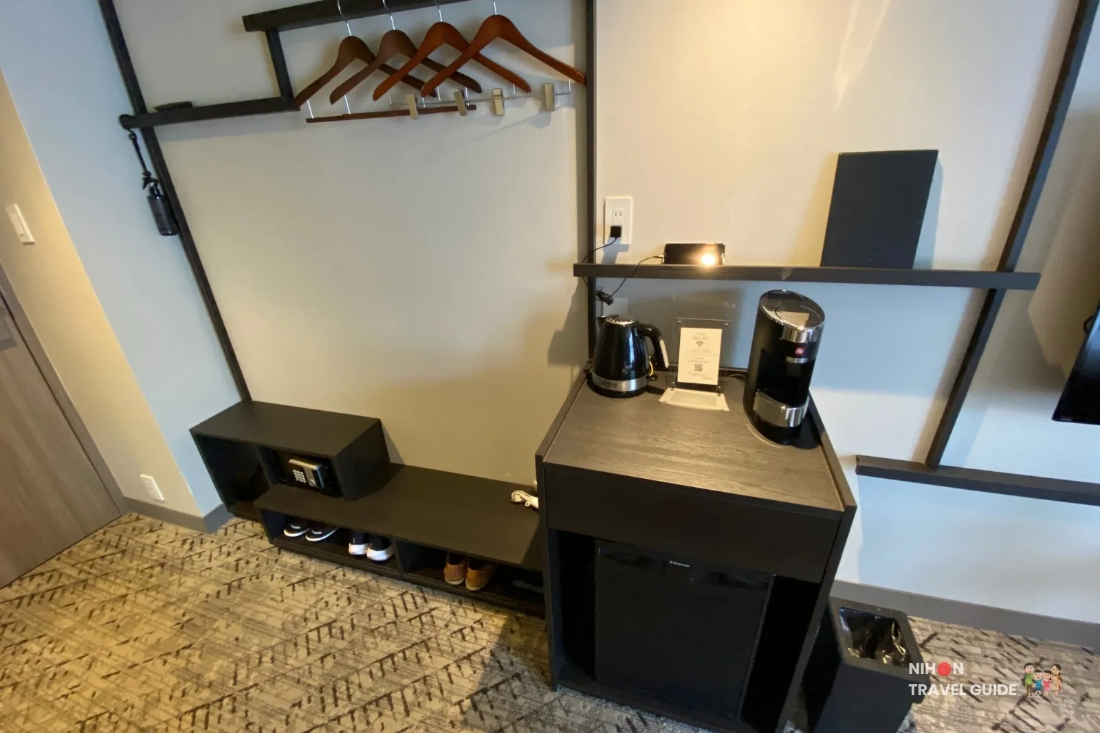 In-room amenity counter at THE BASICS FUKUOKA Moderate Twin with a De’Longhi kettle, illy coffee machine, Wi-Fi card, and an open drawer holding bottled water, hotel mugs, tea, tissues, and coffee capsules.